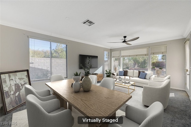 carpeted dining space with a wealth of natural light, ornamental molding, and ceiling fan