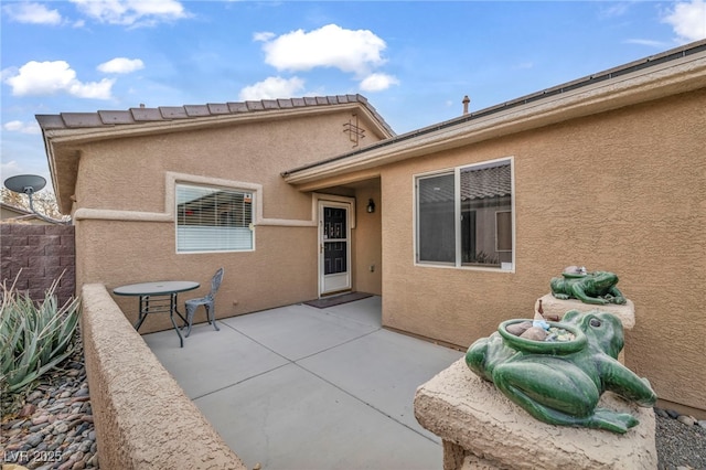 back of property with a patio and stucco siding