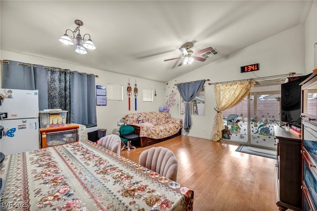 bedroom with access to exterior, light hardwood / wood-style floors, ceiling fan with notable chandelier, vaulted ceiling, and white fridge