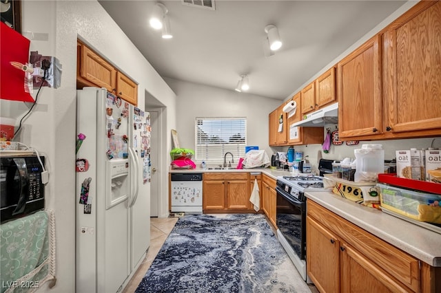 kitchen with light tile patterned floors, vaulted ceiling, a sink, white appliances, and under cabinet range hood