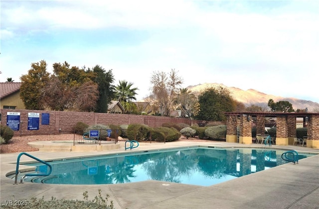 pool with a patio area, fence, and a mountain view