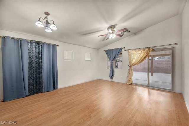 spare room featuring lofted ceiling, visible vents, wood finished floors, and ceiling fan with notable chandelier