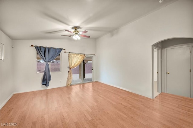 unfurnished room with ceiling fan, arched walkways, vaulted ceiling, and wood finished floors