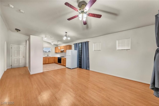 kitchen with light wood-style flooring, stove, vaulted ceiling, light countertops, and freestanding refrigerator