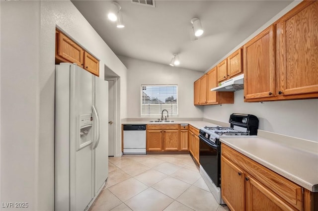 kitchen featuring white appliances, vaulted ceiling, under cabinet range hood, a sink, and light tile patterned flooring