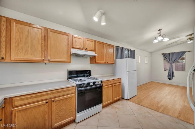 kitchen featuring lofted ceiling, light countertops, light tile patterned flooring, white appliances, and under cabinet range hood