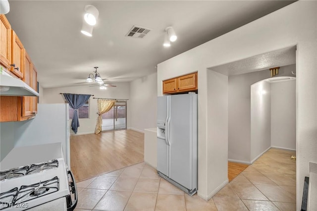 kitchen with light tile patterned floors, lofted ceiling, visible vents, a ceiling fan, and white appliances