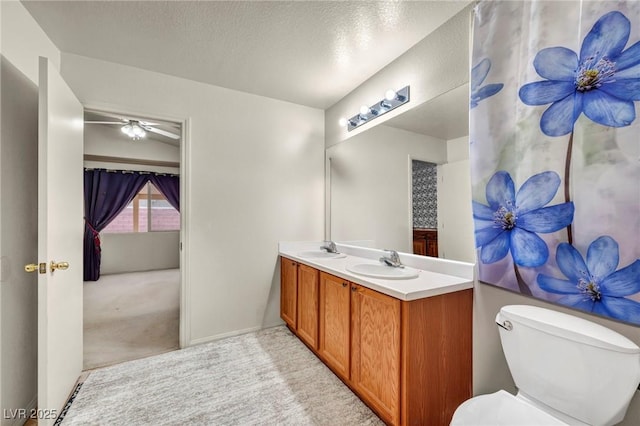 bathroom featuring a sink, a textured ceiling, toilet, and double vanity