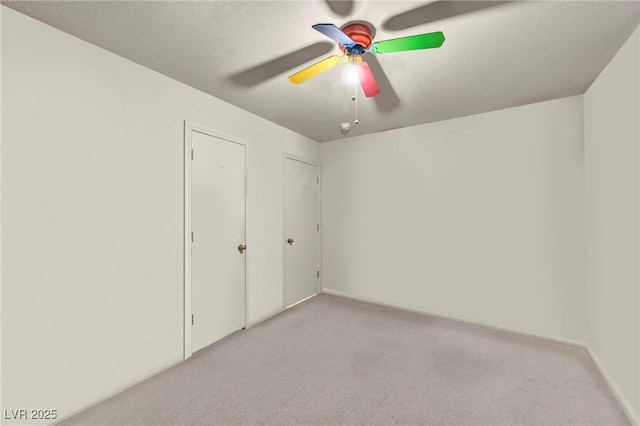 unfurnished bedroom featuring light carpet, ceiling fan, and a textured ceiling