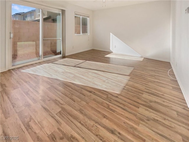 empty room featuring wood finished floors, a ceiling fan, and baseboards