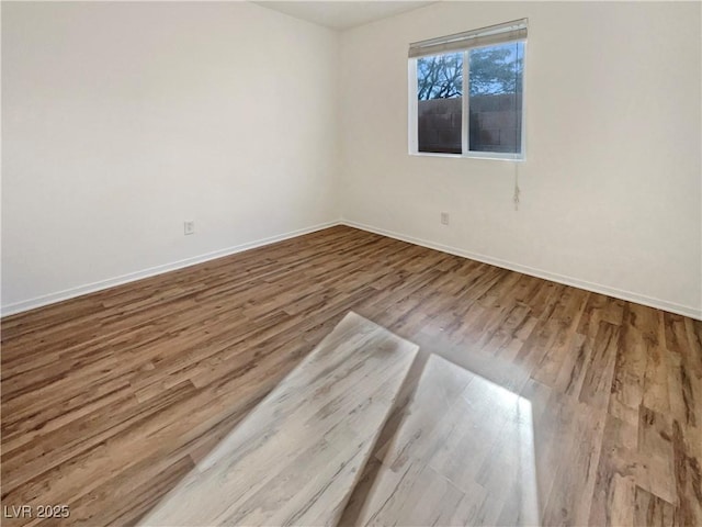 unfurnished room with baseboards and wood finished floors