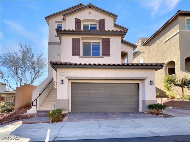 view of front facade featuring an attached garage, stairs, decorative driveway, and stucco siding