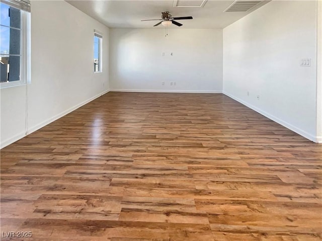 empty room featuring ceiling fan, wood finished floors, visible vents, and baseboards