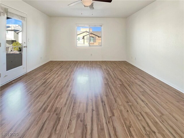 spare room featuring ceiling fan, baseboards, and wood finished floors