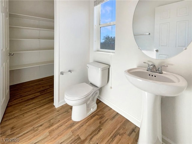 bathroom with wood finished floors, toilet, and baseboards