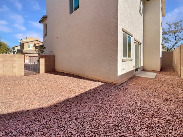 view of property exterior with a gate, a fenced backyard, and stucco siding