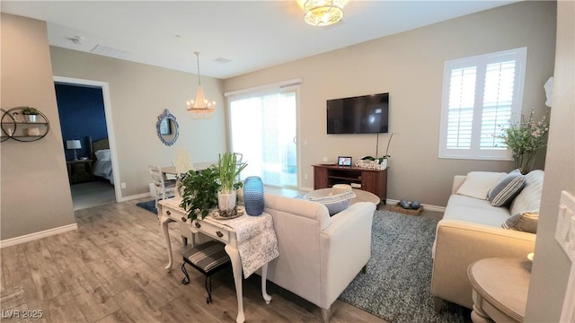 living area with a notable chandelier, baseboards, and wood finished floors