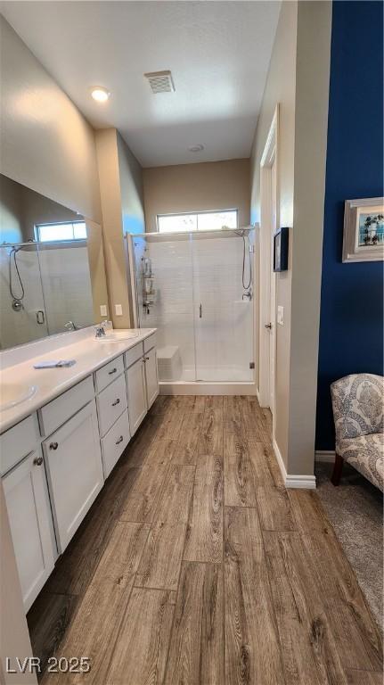 bathroom featuring a shower with door, a wealth of natural light, visible vents, and wood finished floors