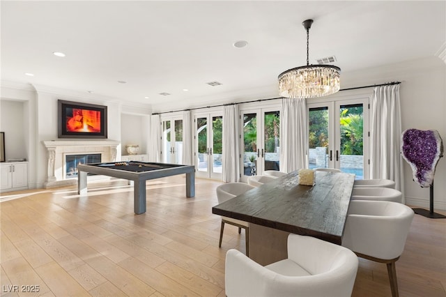 recreation room featuring french doors, ornamental molding, a chandelier, and light hardwood / wood-style flooring