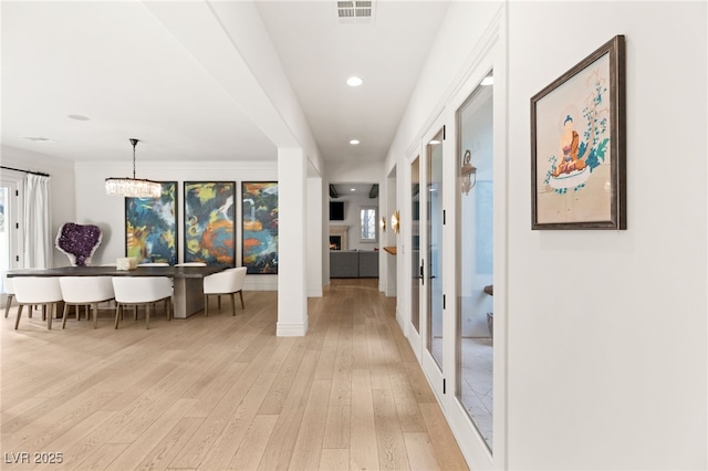 hallway featuring an inviting chandelier and light hardwood / wood-style floors