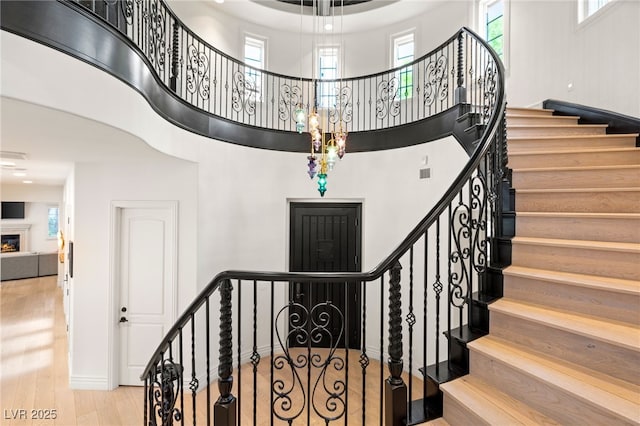 stairs with hardwood / wood-style floors and a high ceiling