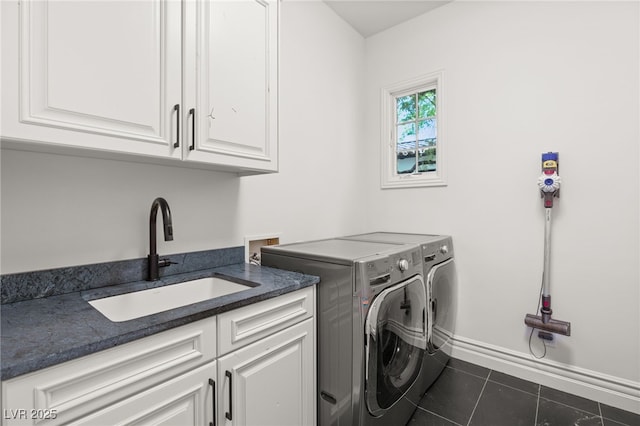 washroom with sink, washer and clothes dryer, cabinets, and dark tile patterned flooring