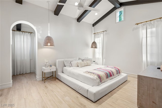 bedroom with ceiling fan, light hardwood / wood-style floors, and vaulted ceiling with beams