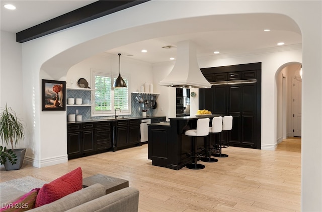 kitchen with a breakfast bar area, a center island, pendant lighting, island exhaust hood, and beam ceiling