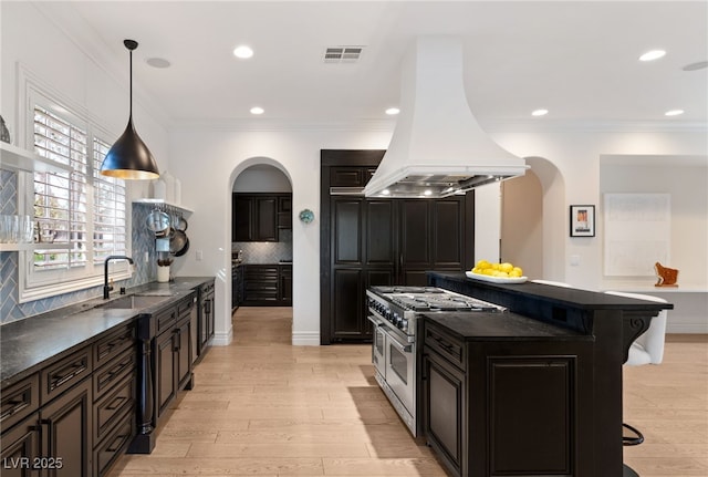 kitchen with a breakfast bar, sink, decorative backsplash, island exhaust hood, and double oven range