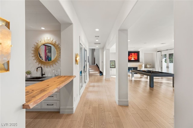 hallway with sink, light hardwood / wood-style floors, and french doors