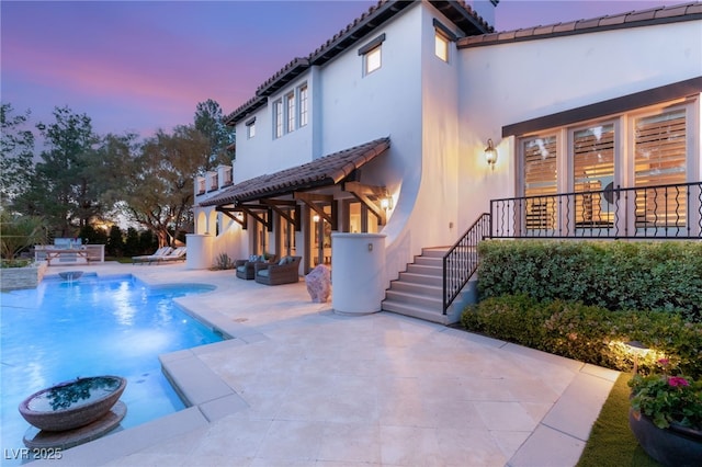 pool at dusk featuring a patio