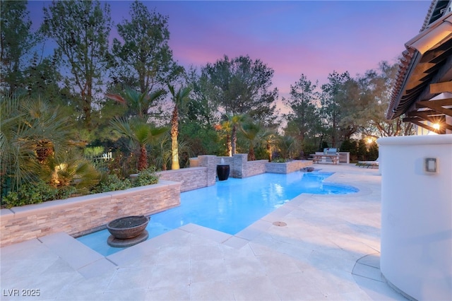 pool at dusk featuring a patio