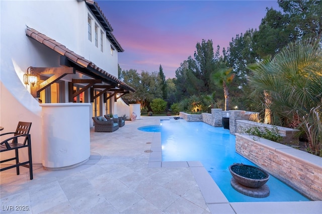 pool at dusk featuring a patio area, water heater, and exterior bar