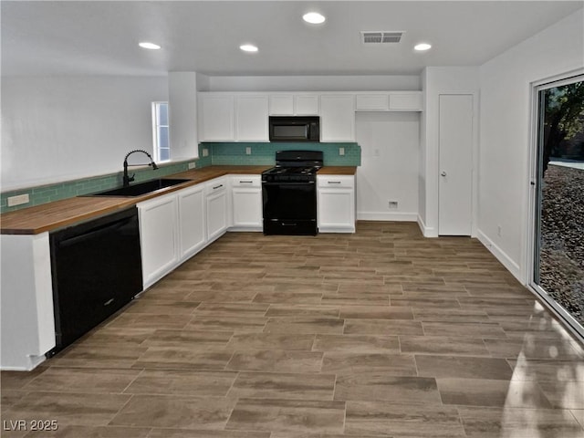 kitchen with white cabinetry, sink, black appliances, and butcher block counters