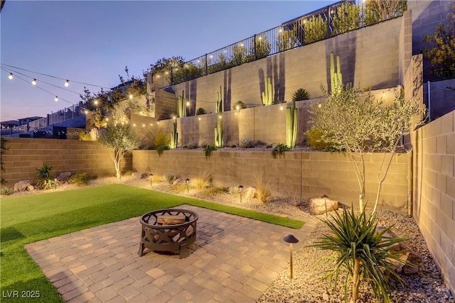 patio terrace at dusk with a lawn and an outdoor fire pit