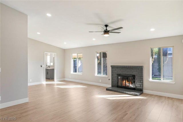 unfurnished living room with plenty of natural light, a fireplace, vaulted ceiling, and light hardwood / wood-style flooring