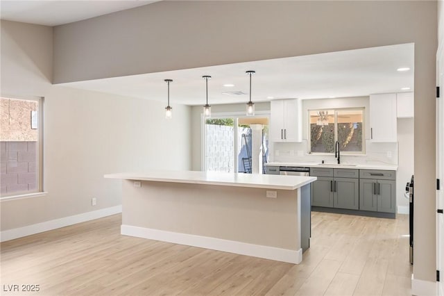 kitchen with gray cabinetry, hanging light fixtures, sink, and white cabinets