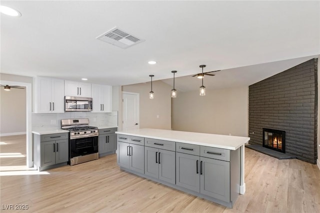 kitchen with appliances with stainless steel finishes, gray cabinetry, white cabinets, and backsplash