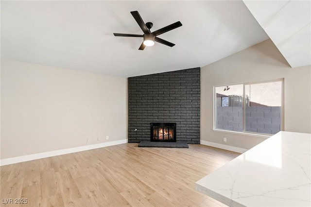 unfurnished living room featuring lofted ceiling, a fireplace, ceiling fan, and light wood-type flooring