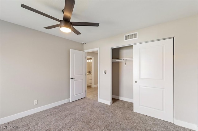 unfurnished bedroom featuring ceiling fan, light colored carpet, and a closet