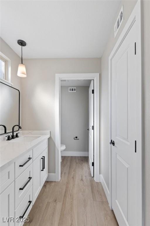 bathroom featuring wood-type flooring, toilet, and vanity