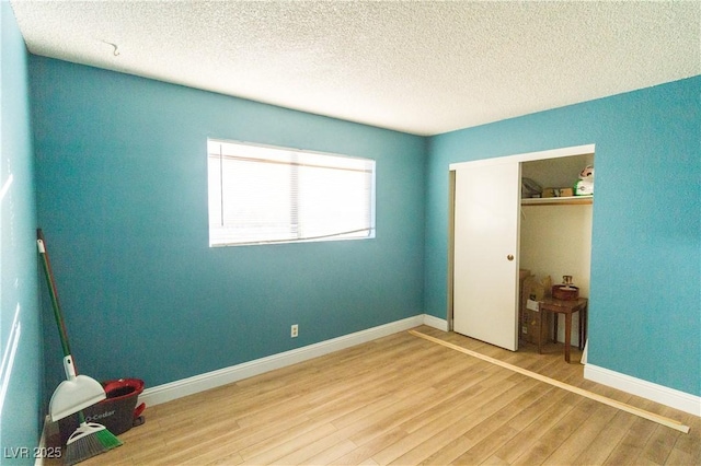 unfurnished bedroom with wood-type flooring, a closet, and a textured ceiling