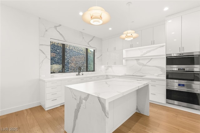 kitchen featuring a kitchen island, tasteful backsplash, sink, white cabinets, and hanging light fixtures