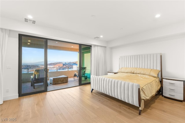 bedroom featuring access to exterior, light hardwood / wood-style flooring, and a mountain view