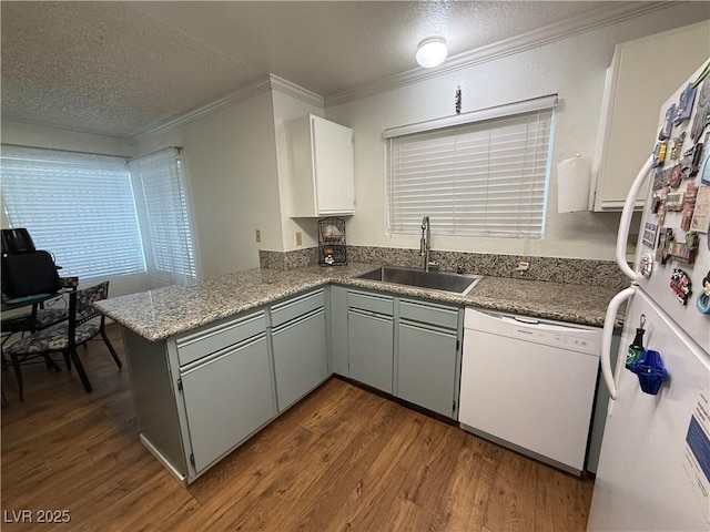 kitchen with sink, crown molding, white appliances, white cabinetry, and kitchen peninsula