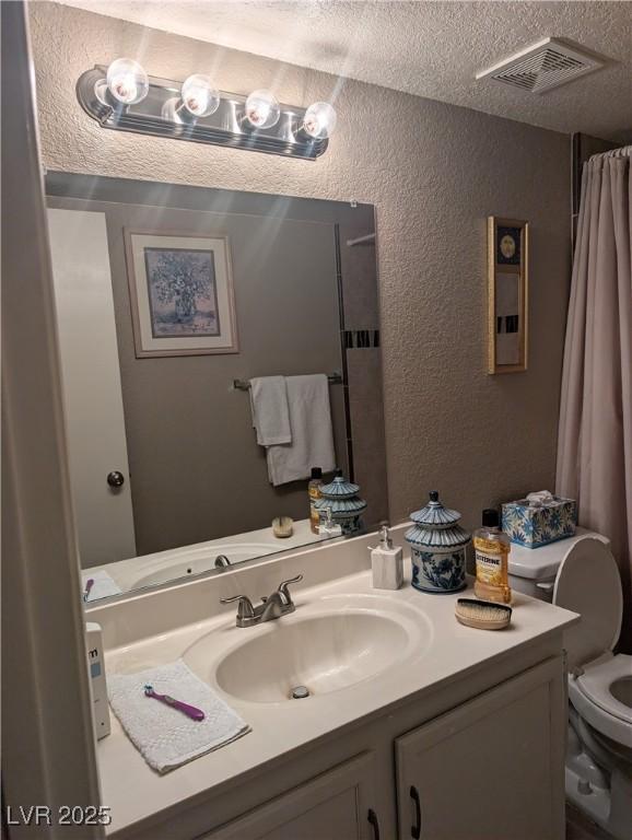 bathroom featuring vanity, toilet, and a textured ceiling