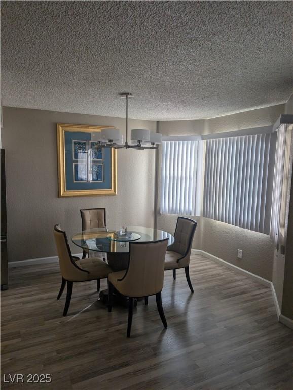 dining area featuring dark wood-type flooring, a chandelier, and a textured ceiling