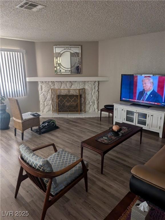 living room with hardwood / wood-style flooring, a fireplace, and a textured ceiling