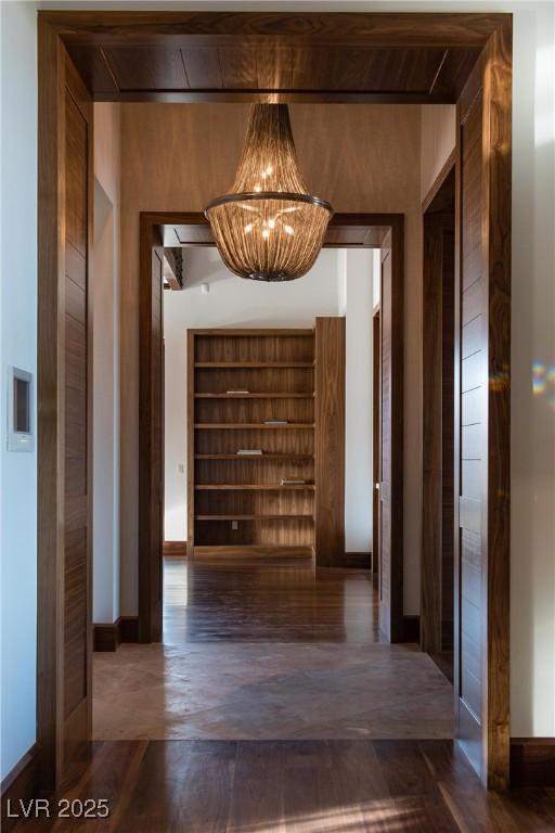 hall with dark wood-type flooring and a chandelier