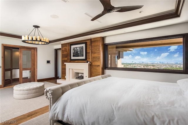 bedroom with ornamental molding, ceiling fan with notable chandelier, and hardwood / wood-style floors